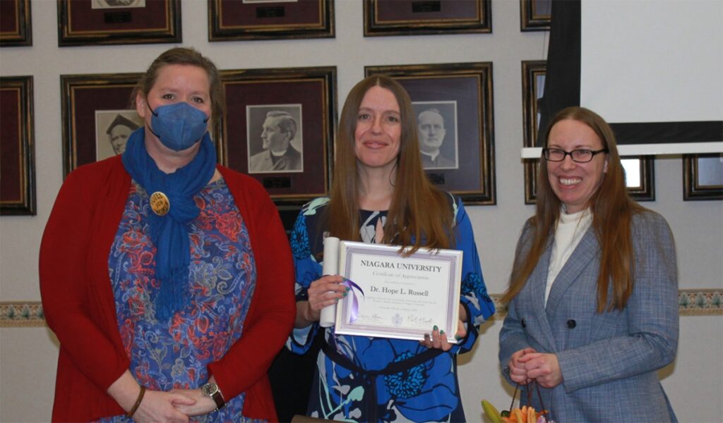 Dr. Shannon Risk, professor of history and former director of the women’s studies program (left), and Dr. Carrie Glenn, assistant professor of history and current director (right) recognize Dr. Hope Russell for her 20 years of service to the program.