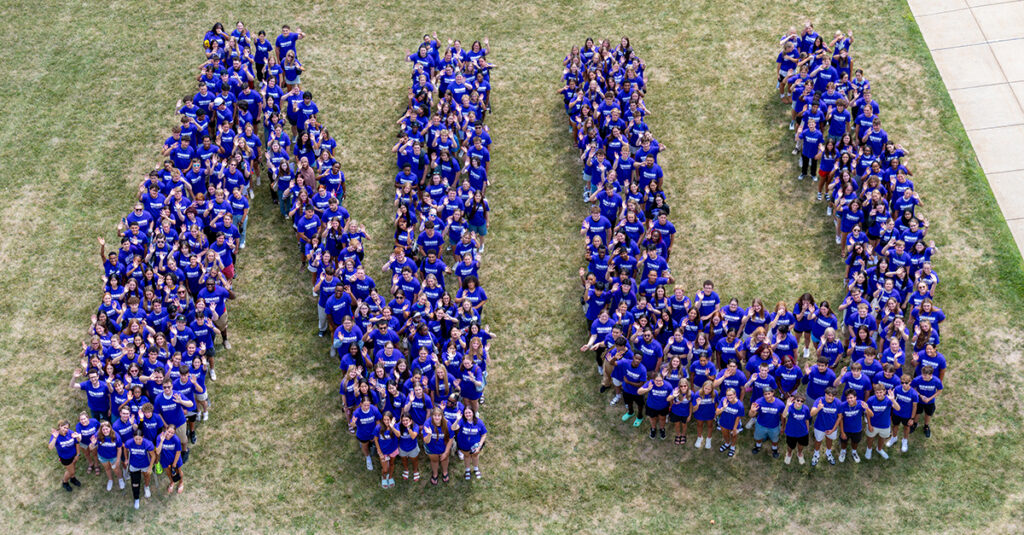 Incoming Students wearing purple shirts and standing to form the letters NU