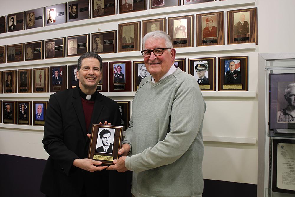 Steve Stojanovich accepts a plaque honoring his uncle, Stephen Slaback, from father maher