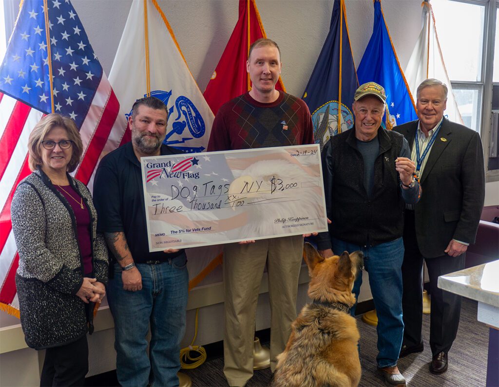 Karl Hinterberger, Niagara University veteran services program director (second from left), accepts a $3,000 donation on behalf of Dog Tags New York from Grand New Flag owner Philip Kauppinen (center).They are pictured with Dr. Debra Colley, Niagara University executive vice president; Joe Ruszala, co-founder of Dog Tags New York; Niagara County Legislator David Godfrey; and Gunner.