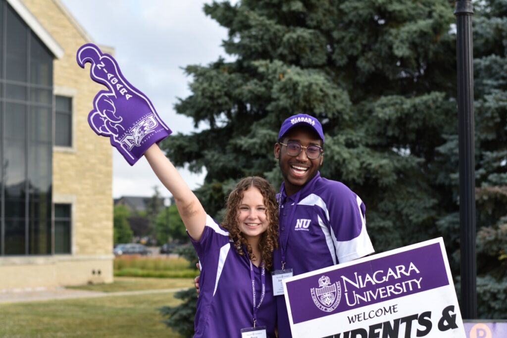 Two orientation leaders greet new students and parents to the Niagara University campus during the 2022 Summer Orientation event.