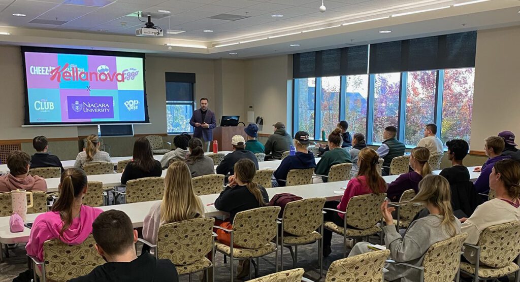 Man giving presentation in front of large group of students.