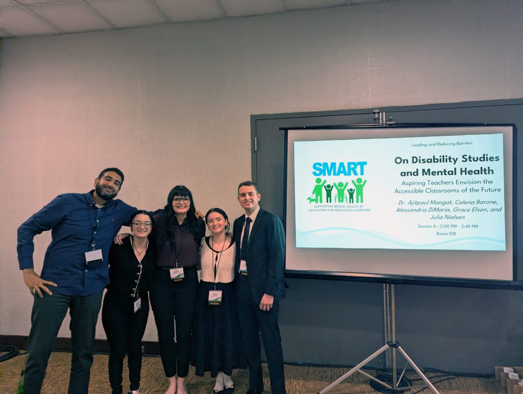 Professor with four students in front of a presentation screen.