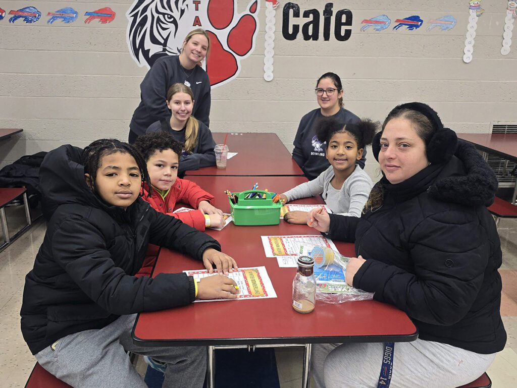 Colleges students working with elementary school students at a table
