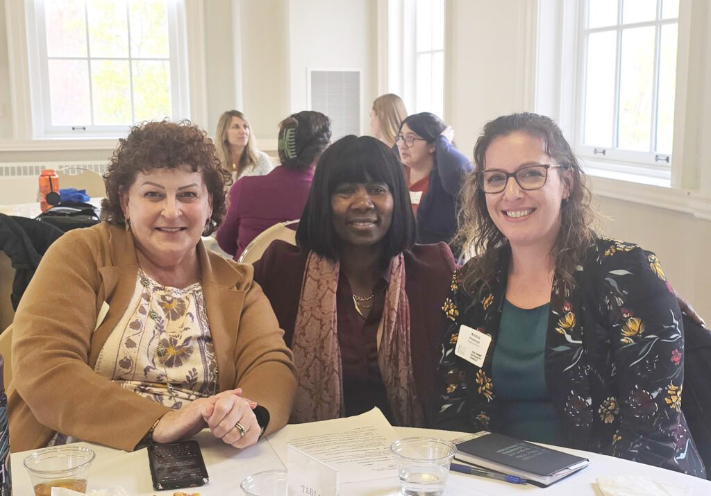Three women at a table during a conference