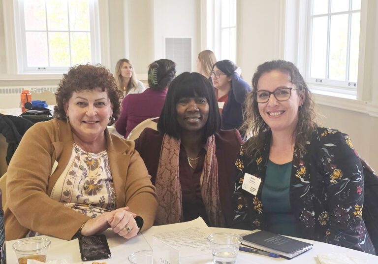 Three women at a table during a conference