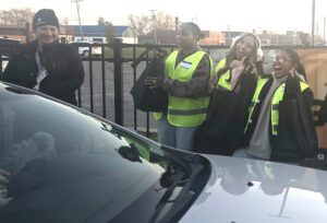 College students hand out bags of food to a car.