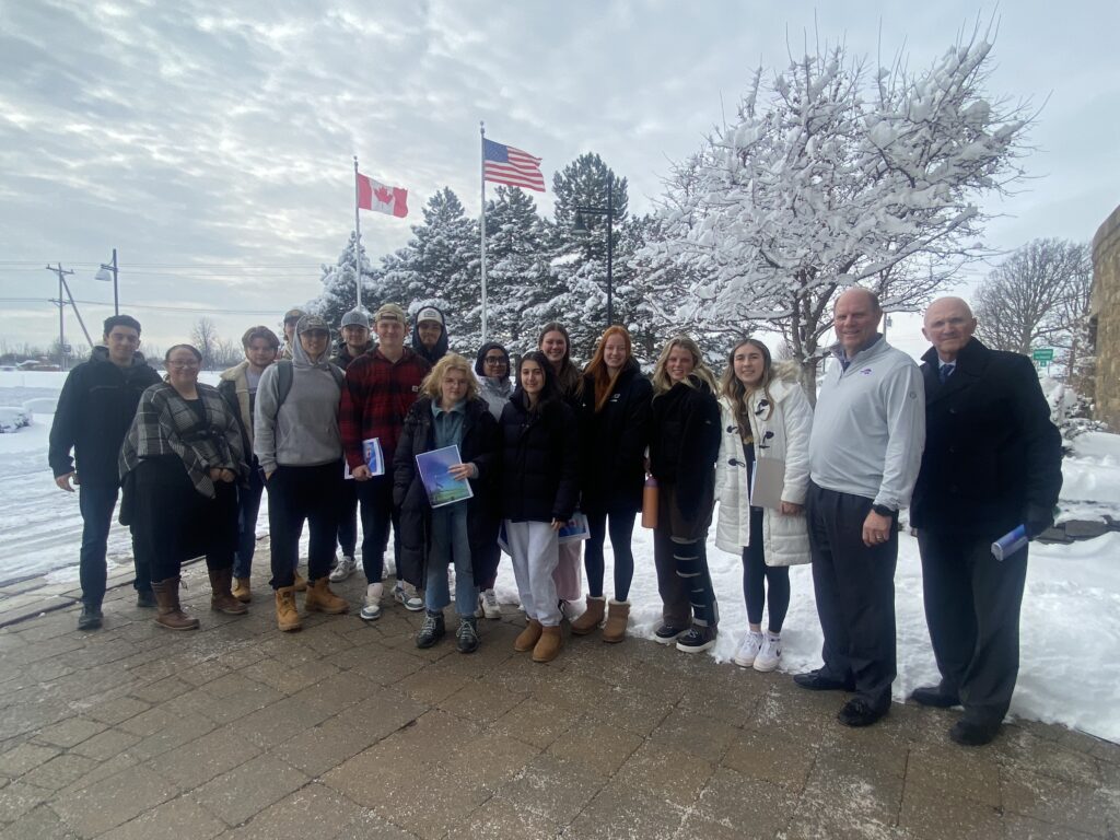 Students and faculty in front of American and Canadian flags