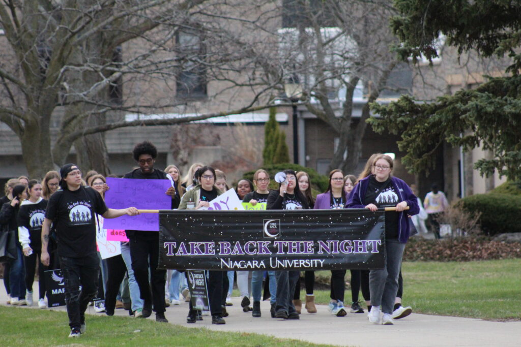 Niagara University students carry a Take Back the Night banner on campus in April 2025.