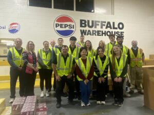 Students in front of a Pepsico Buffalo Warehouse sign wearing reflective vests