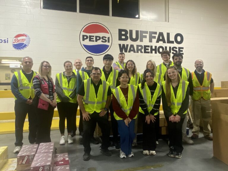 Students in front of a Pepsico Buffalo Warehouse sign wearing reflective vests