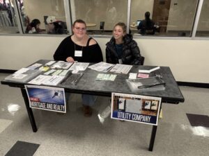 Two students participating at a services table within the Community Action Poverty Simulation