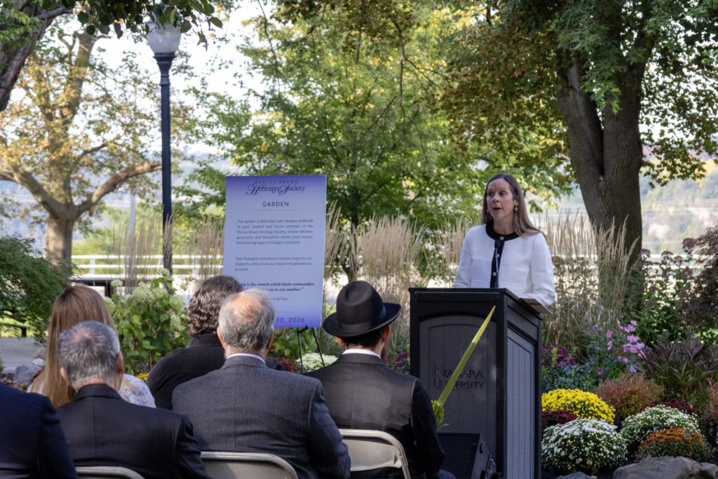 Jaclyn Drozd at a podium with the garden in the background.