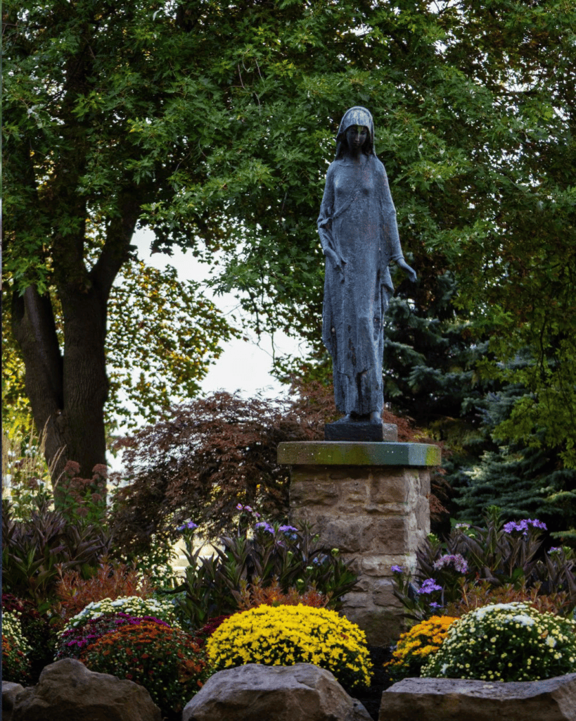 A statue with flowers below it.